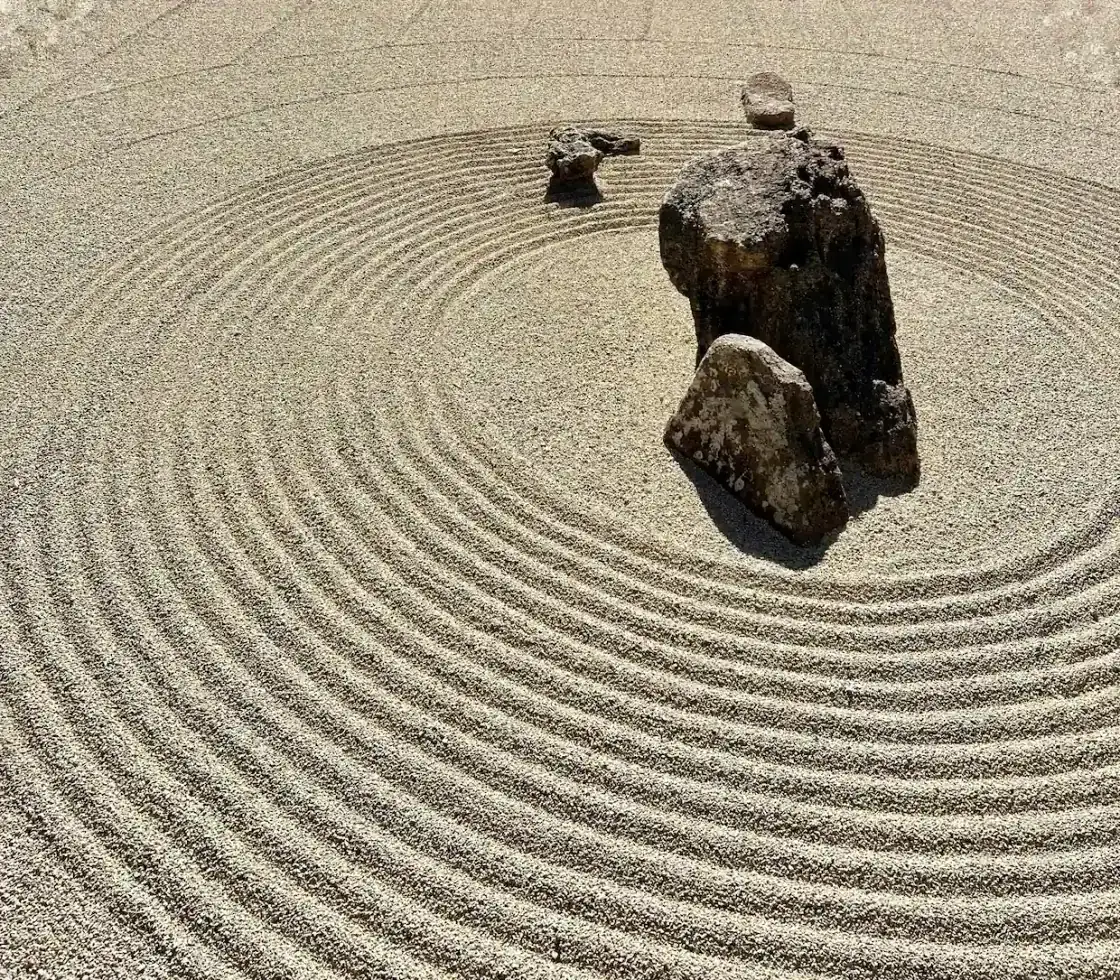 A raked Japanese zen garden with concentric circles of gravel around standing stones